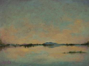 A serene lake with a distant mountain under a calm sky.