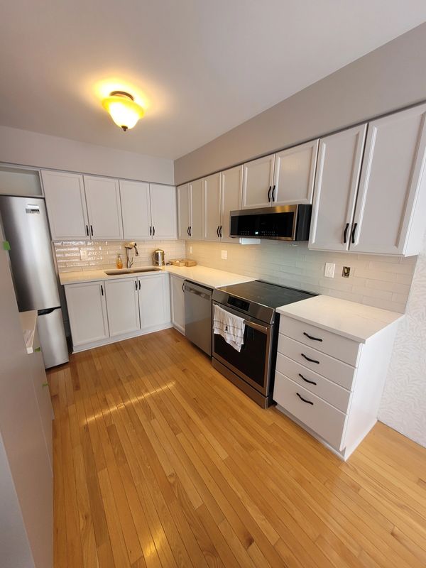 Cuisine moderne avec plancher en bois et appareils en acier inoxydable.