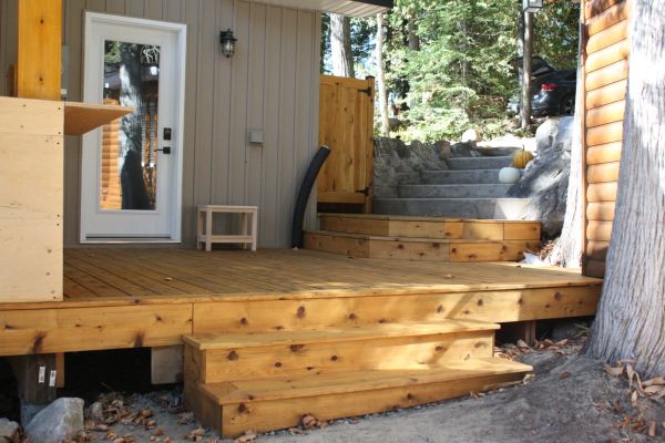 Terrasse en bois avec des marches menant à une porte blanche.