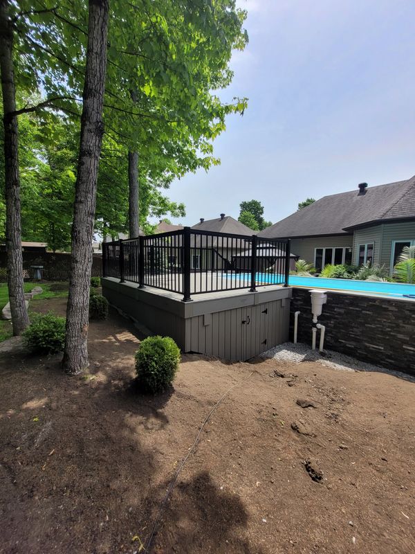 Piscine surélevée avec clôture noire dans un jardin.