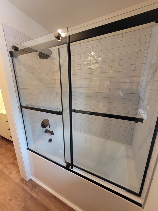 Baignoire moderne avec paroi en verre et carrelage métro blanc.