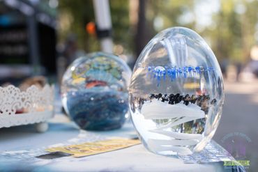 Clear glass paperweights with intricate designs inside on display outdoors.