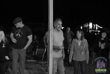 Black and white photo of people chatting outdoors at night near a light post.