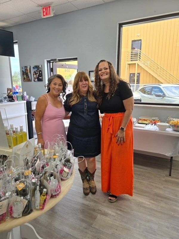 Three women smiling inside a store with gift bags.