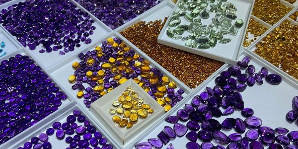Various colored gemstones arranged in trays.