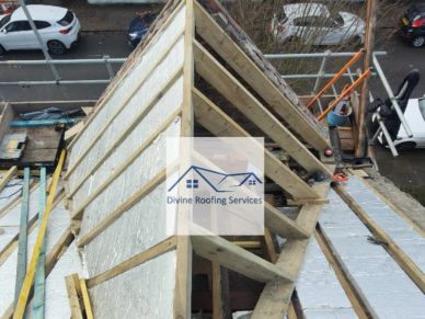 Roof under construction with wooden beams and insulation.