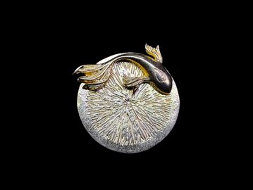 Metallic fish sculpture on a circular base.
