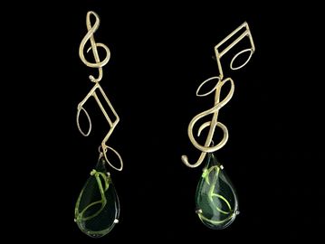 Gold earrings with musical notes and green teardrop gems.