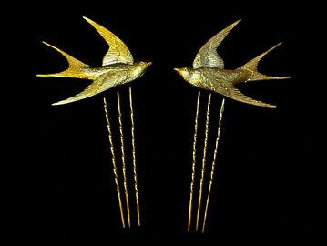 Pair of gold bird hairpins with intricate designs.