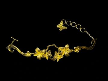 Elegant gold floral bracelet on black background.