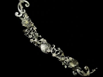 Intricate silver bracelet with floral designs.