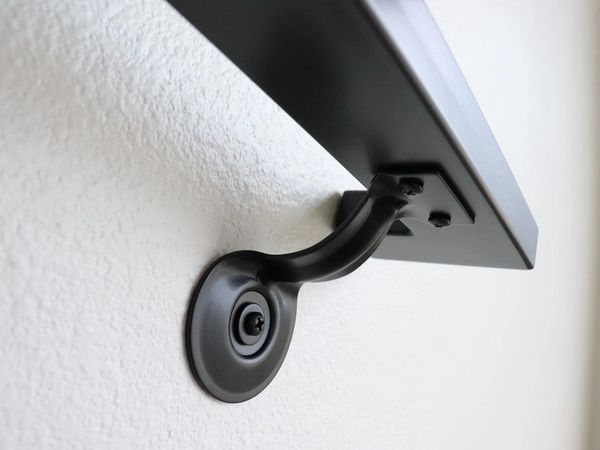 Close-up of a black metal bracket mounted on a white wall.