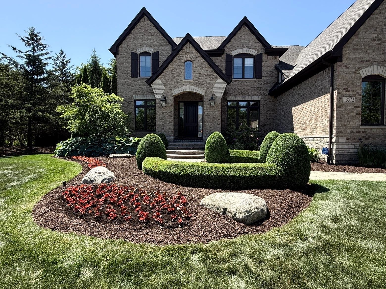 Beautiful brick house with manicured front yard and hedge garden.