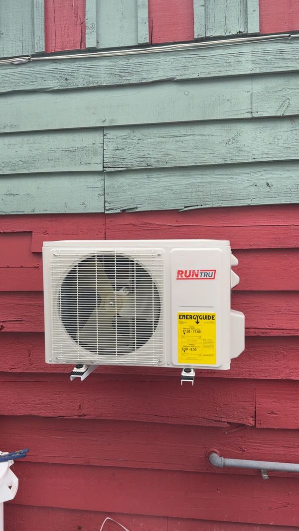 White RUNTRU air conditioning unit mounted on red and blue wooden wall.