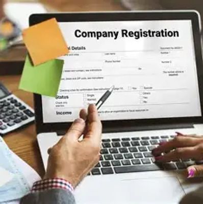 Two people filling out a company registration form on a laptop.
