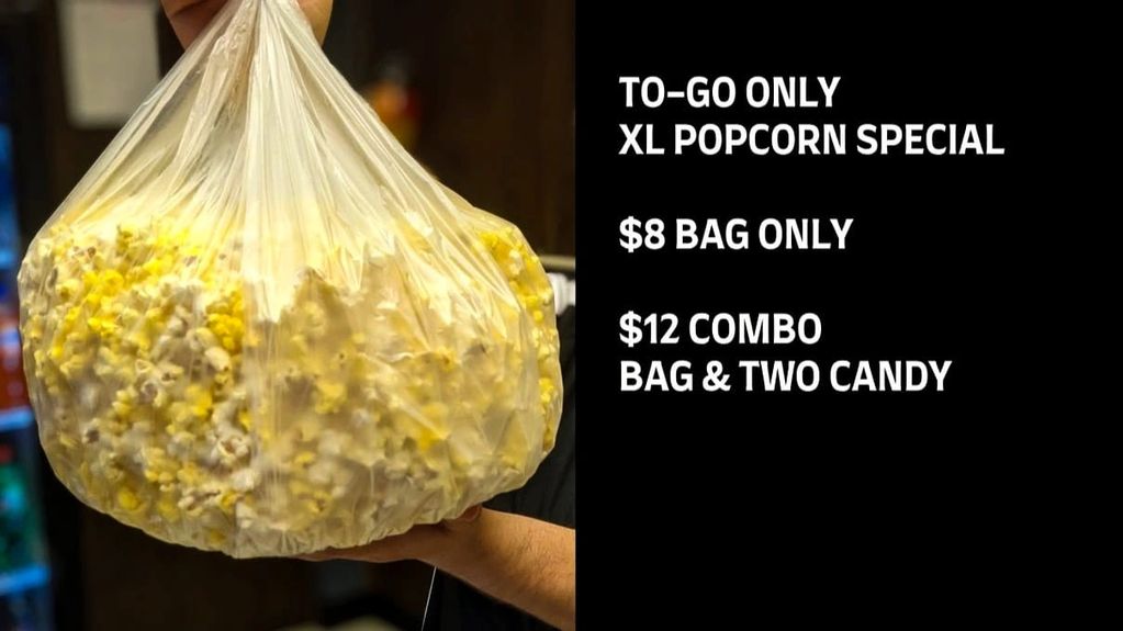 Hand holding a large bag of popcorn with a special offer sign.