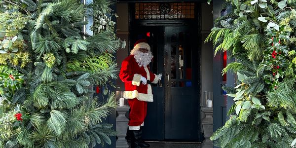 Santa Claus standing at a decorated door.