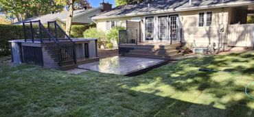 Backyard with a wooden deck and above-ground hot tub surrounded by grass.