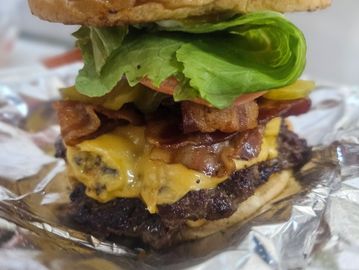 A close-up of a bacon cheeseburger with lettuce and melted cheese.