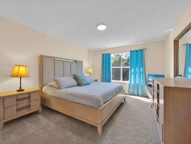 Bright bedroom with blue curtains and wooden furniture.