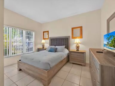 Modern bedroom with large window and neutral tones.