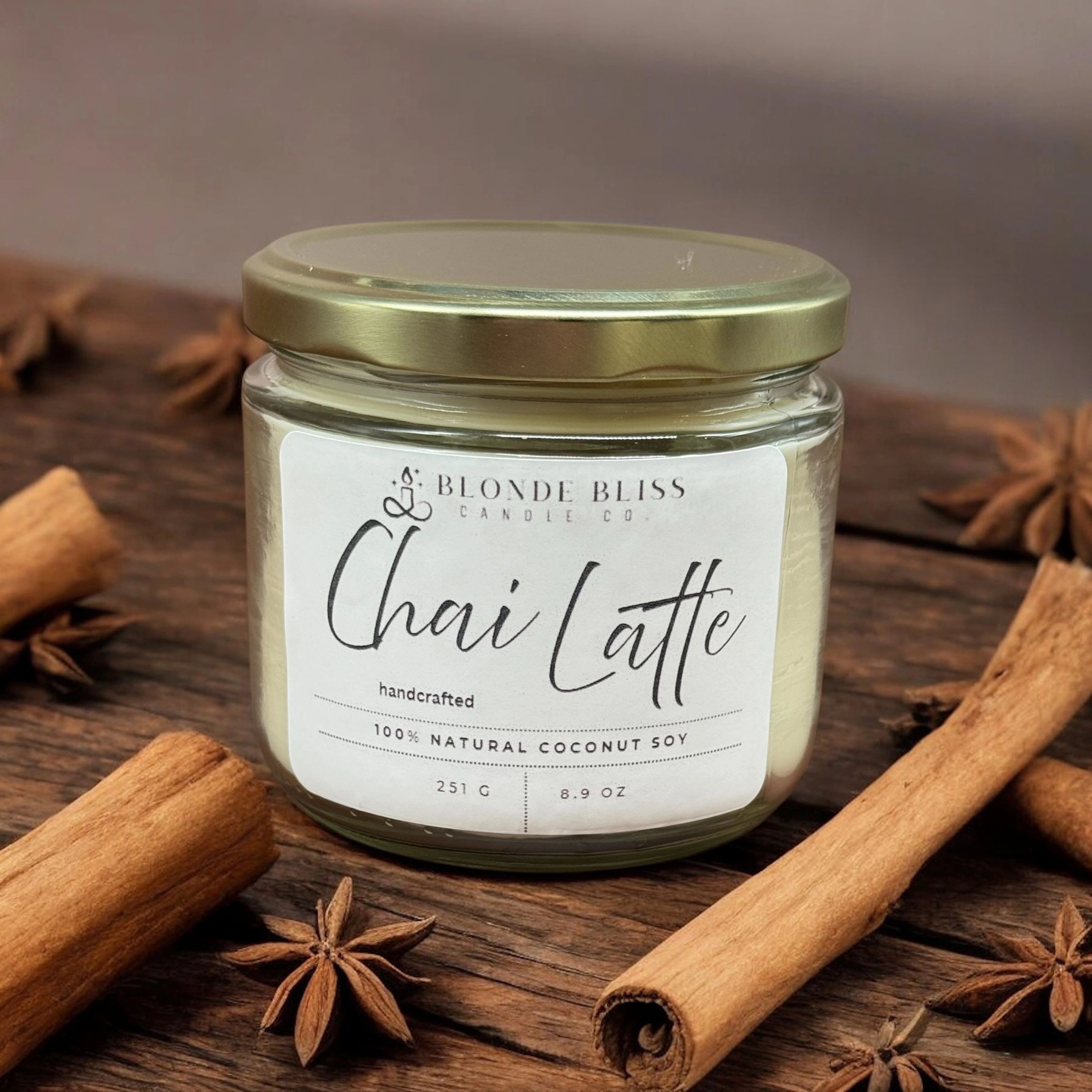 A chai latte scented candle surrounded by cinnamon sticks and star anise.