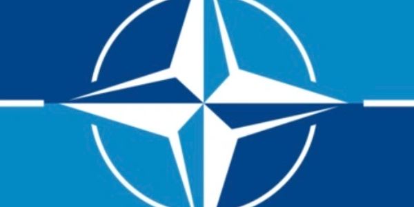 Logo of NATO, featuring a four-pointed compass star in blue and white colors.