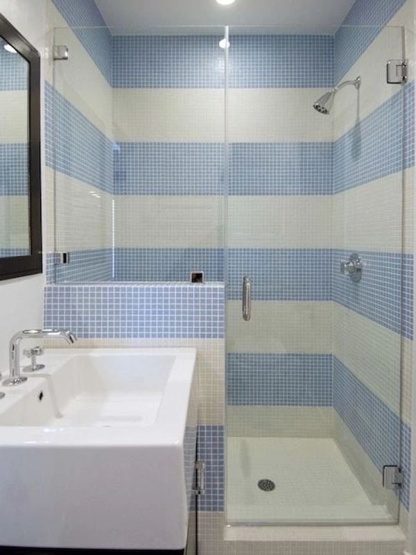 Modern bathroom with blue and white tiled shower and a sleek white sink.