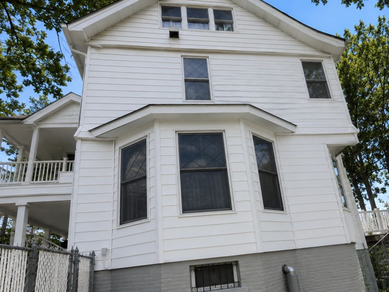 White two-story house with multiple windows and gray brick foundation.
