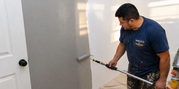Man painting a wall gray with a roller.