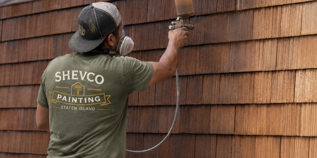Painter spray painting wooden shingles.