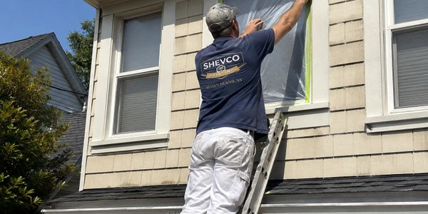 Painter preparing a window for painting on a house exterior.