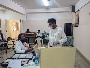 Medical professionals engaged in a discussion inside a clinic room.
