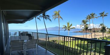 Balcony view of a beach with palm trees and clear skies.