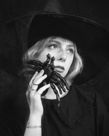 Woman in witch hat holding a large spider.