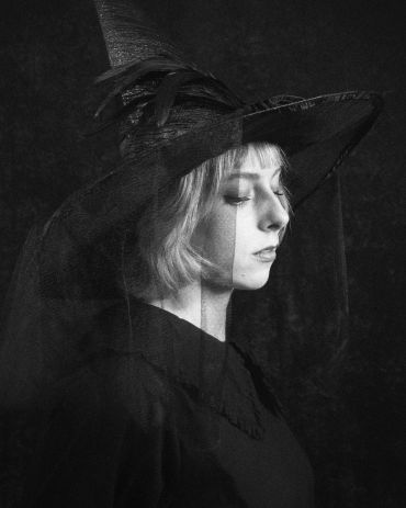 Profile of woman in witch hat with veil.
