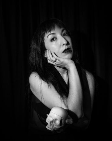 Woman posing with a skull in black and white portrait.