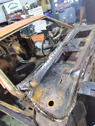 Partially disassembled vintage car undergoing restoration in a workshop.