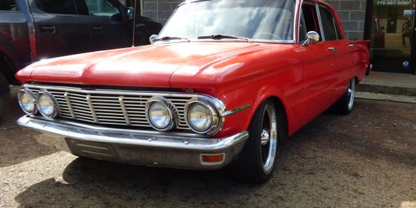 Classic red vintage car with chrome details parked outdoors.