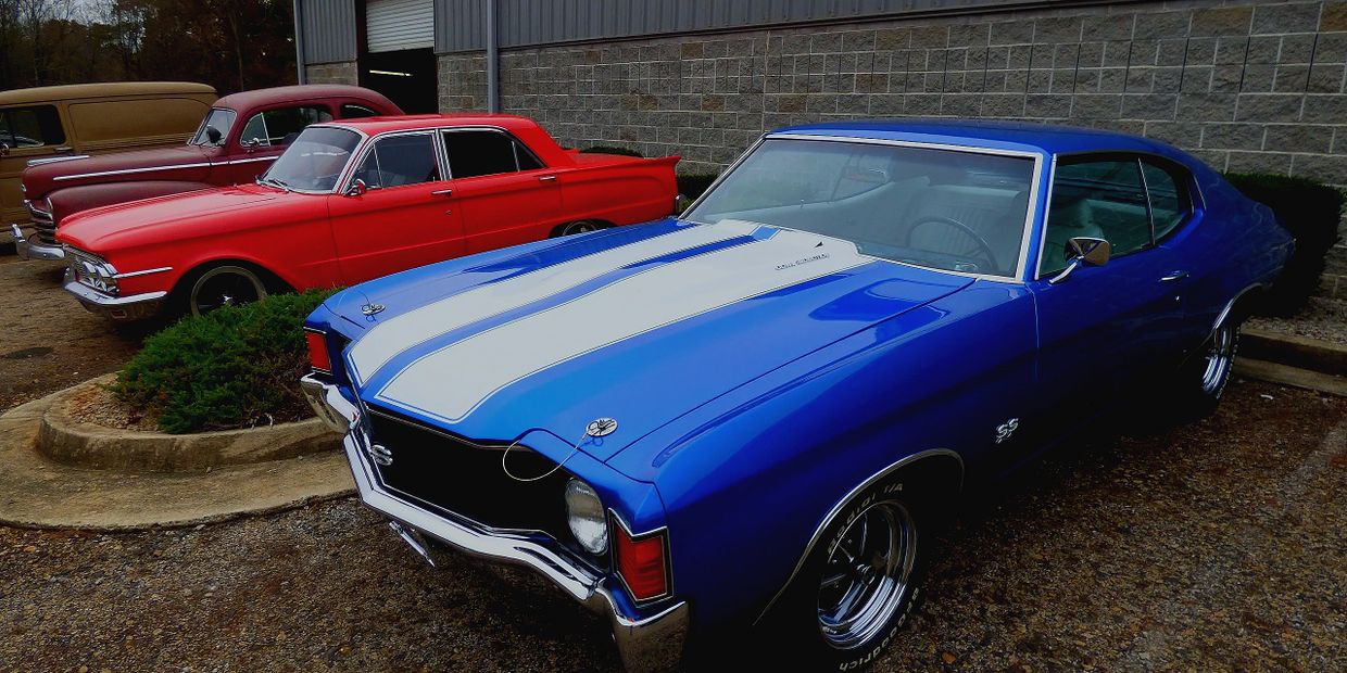 Blue and red classic cars parked outside a building.