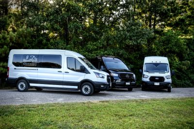 Three vans parked outdoors near trees.
