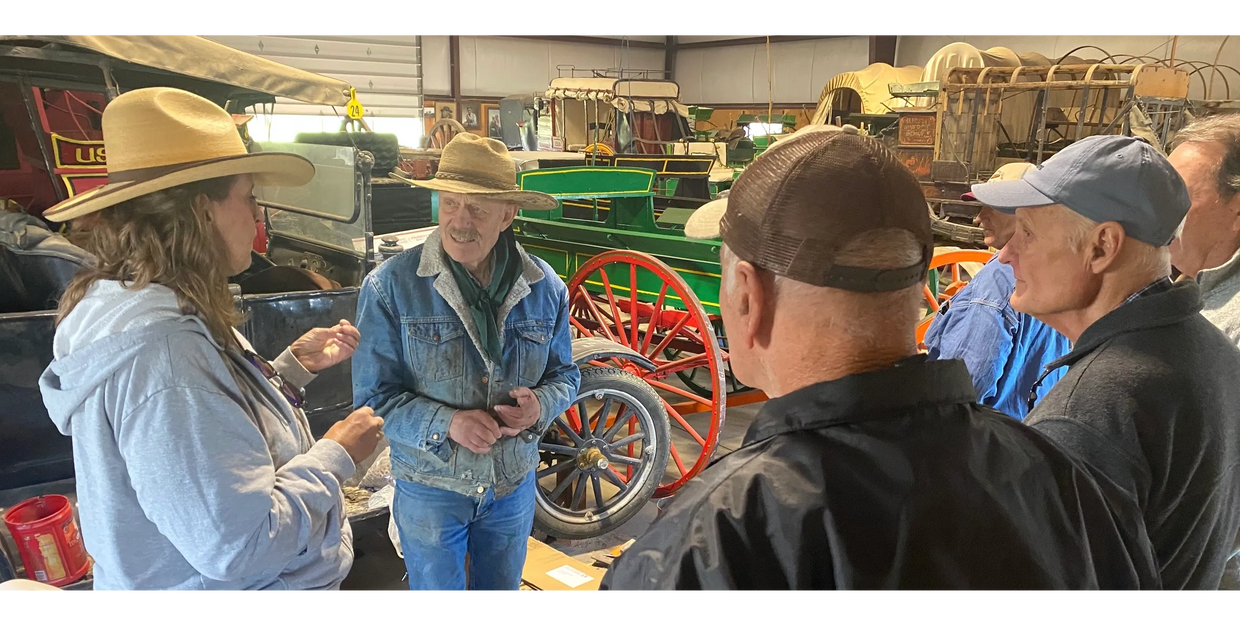 Group of people talking, surrounded by historical vehicles.