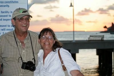 Smiling couple posing by the waterfront at sunset.
