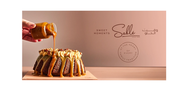 Caramel sauce being poured over a delicious cake topped with cream and nuts.