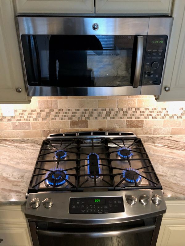 Modern stainless steel stove with blue flames on gas burners.