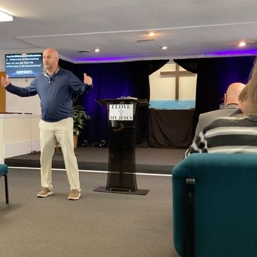 Image of Pastor Dwayne speaking to the congregation.  He's waving his hands around like normal.