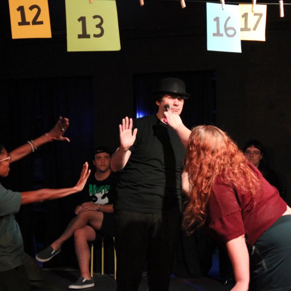 People acting in a theatrical play with a spotlight.