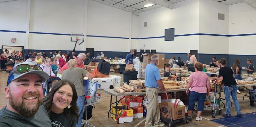 People shopping for bread and groceries in a large indoor market or community center.