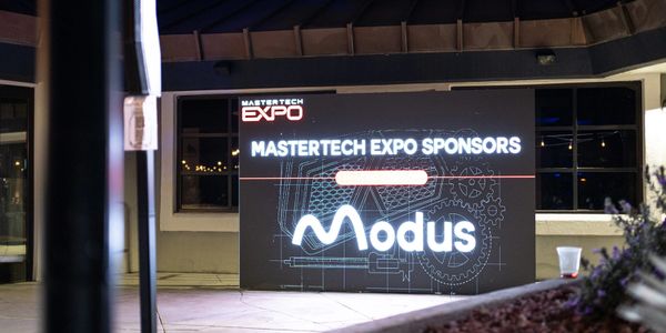 Illuminated sponsor sign for Modus at a Mastertech Expo event.