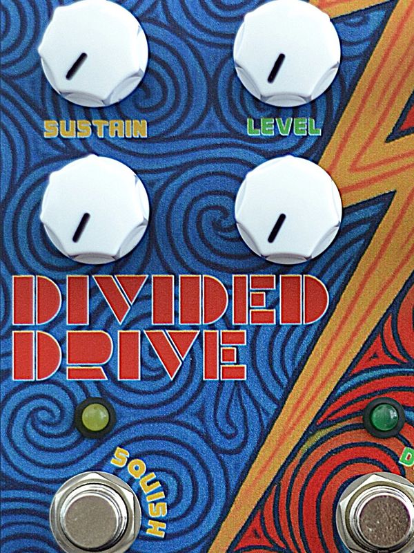 Close-up of a guitar effects pedal labeled 'Divided Drive' with control knobs and footswitches.